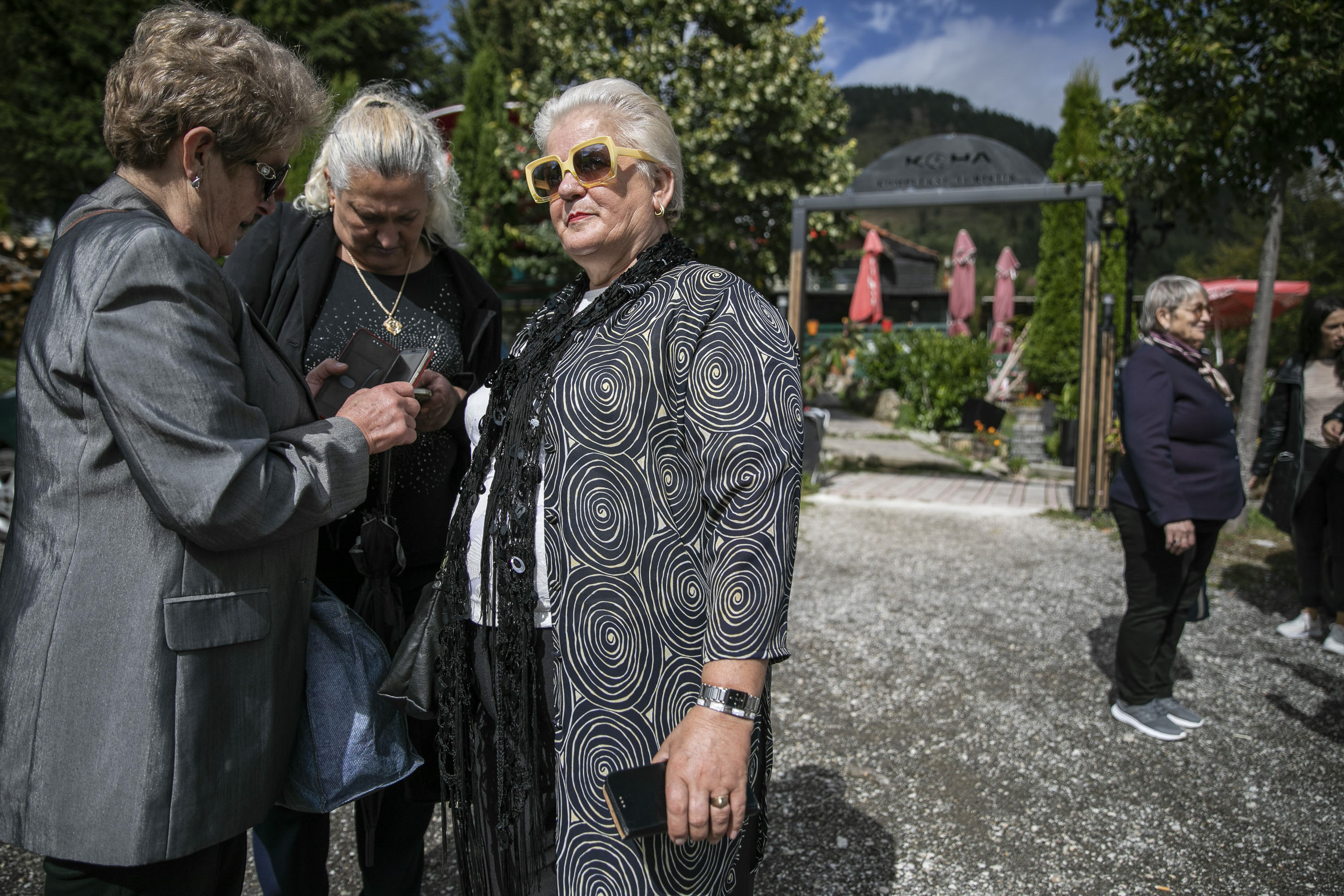 Elderly women on their smartphones at the entry of a restaurant at the Prevalla Pass during an organized bus tour for the women of Prishtina.